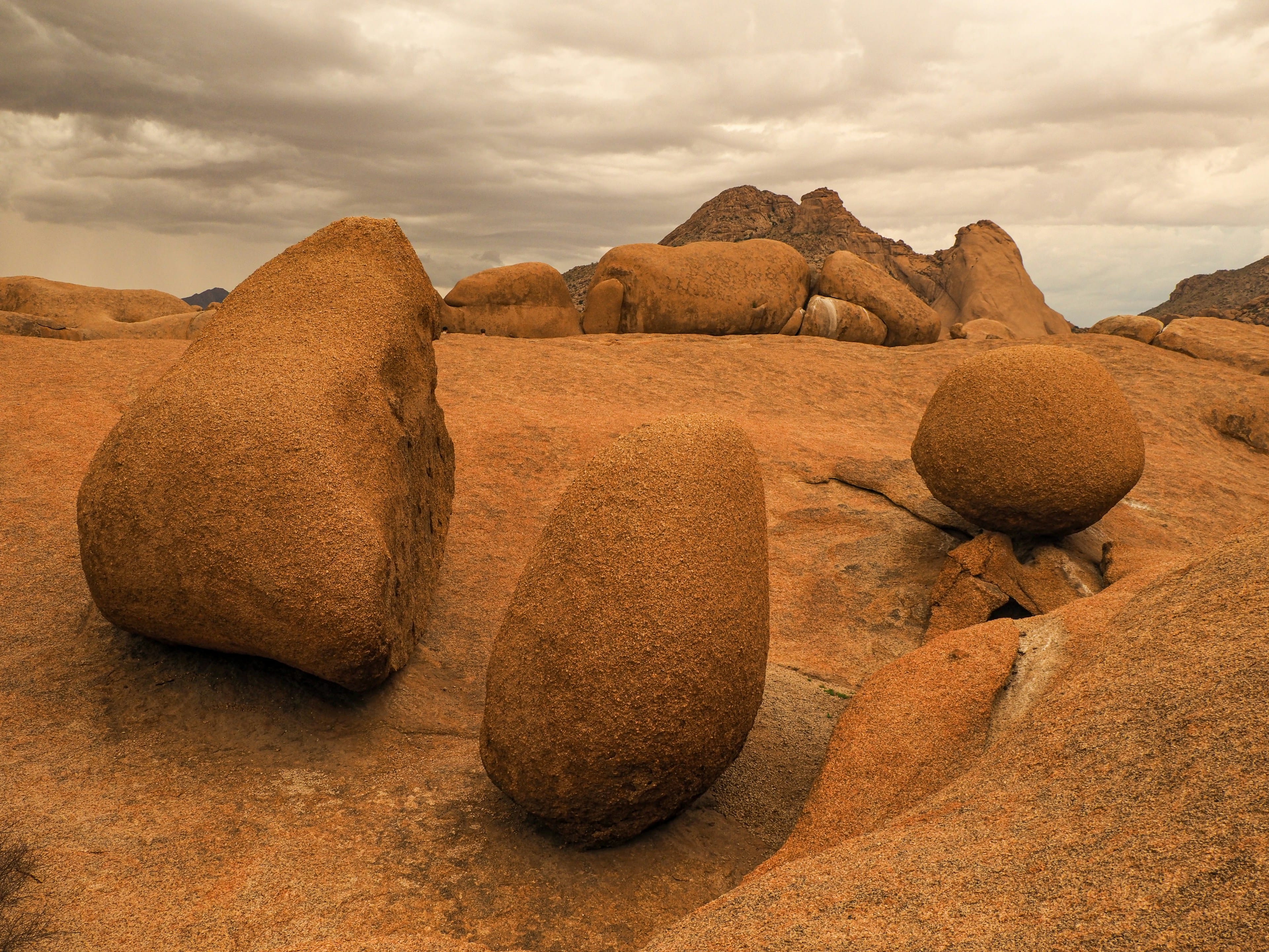 Weathered granite boulders on a rocky desert plain under a stormy sky